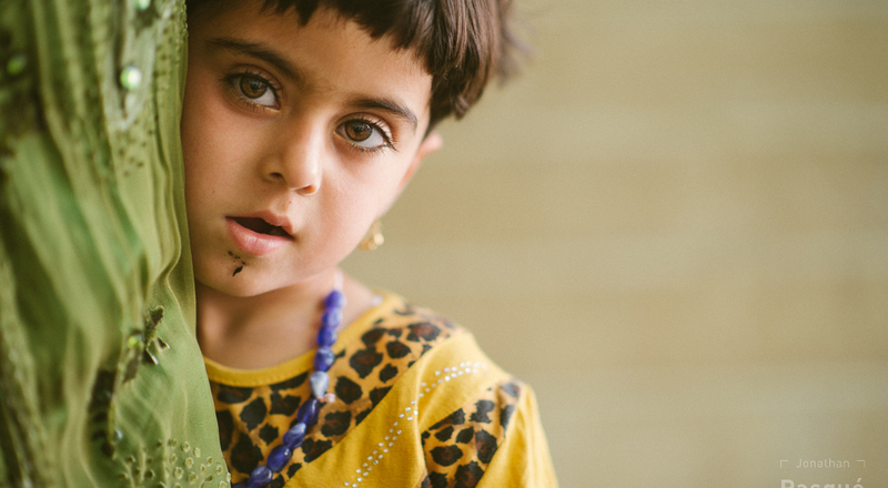 Une jeune fille yézidie intimidée par le photographe se réfugie dans le jupon de sa mère.
